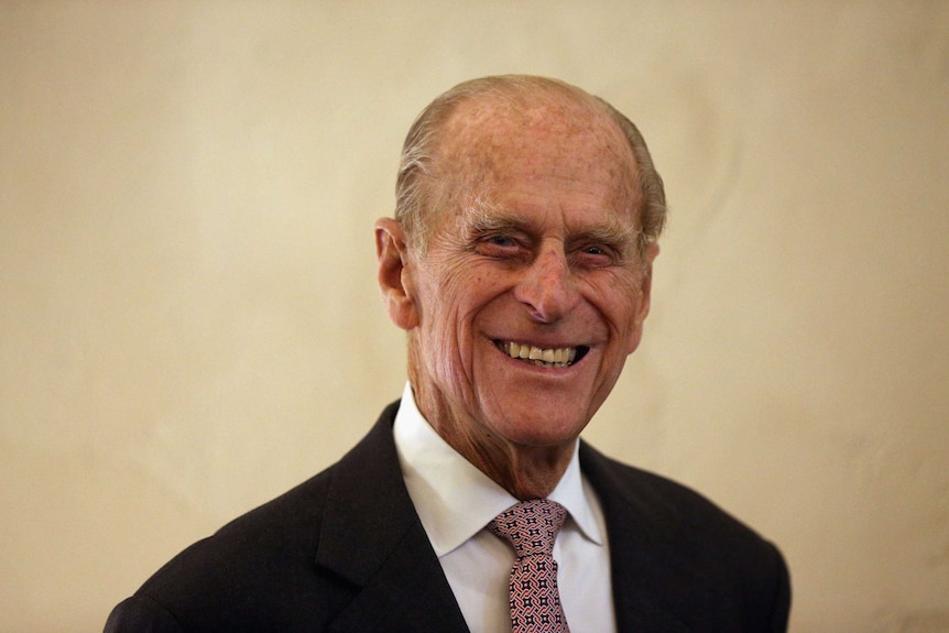 Prince Philip, wearing a suit, smiles in 2012.