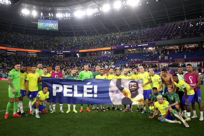 A banner is held by Brazil players with Pele written on it and an image of his face