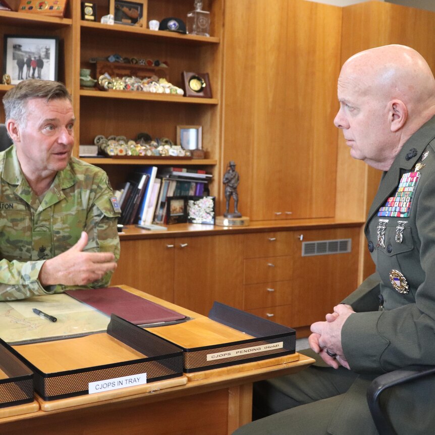 Greg Bilton and David Berger talk in an office in military attire
