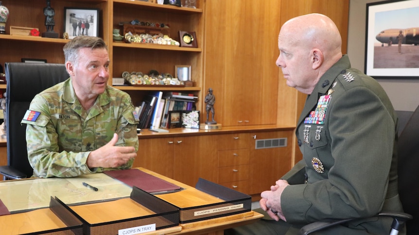 Greg Bilton and David Berger talk in an office in military attire