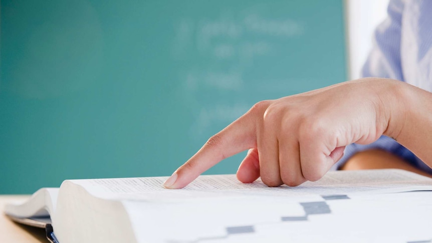 A finger rests over an entry of an open dictionary.