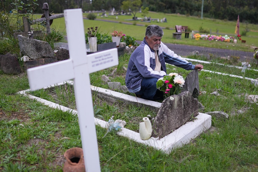 A man sitting next to a grave in a cemetery