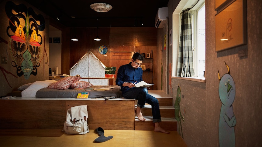 A man sits reading in a neat and tidy loft.