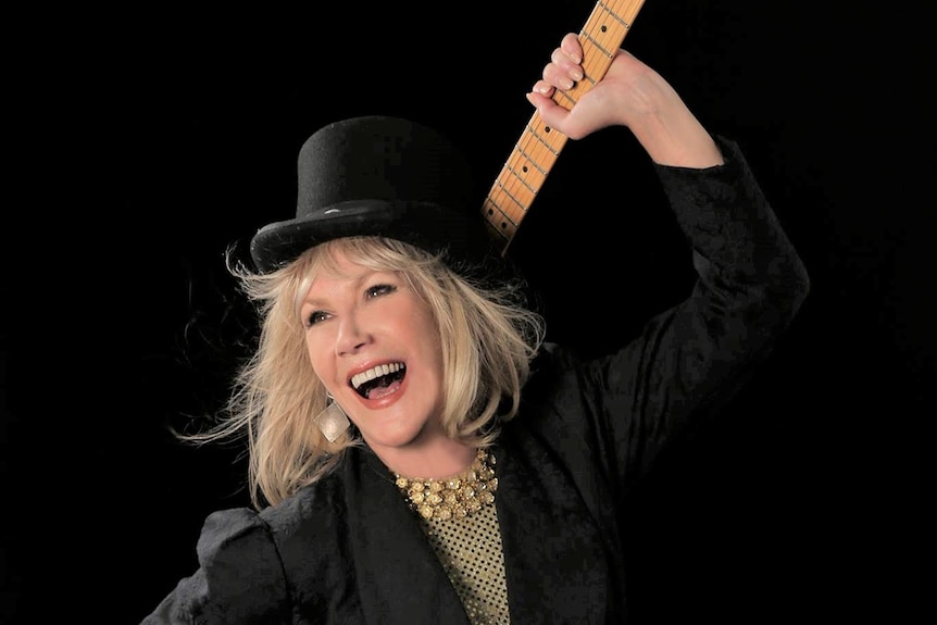 Wendy Stapleton holds a guitar in a promotional photo.