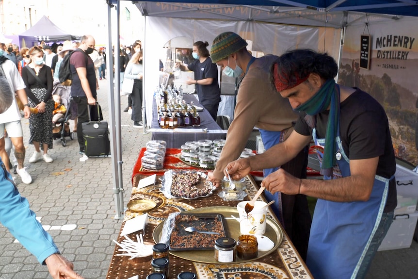 A man prepares food in an outdoor market stall.