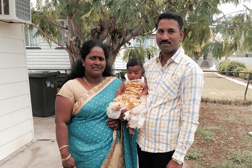 A Sri Lankan couple stand holding a baby girl