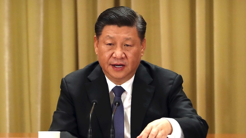 Presiden China Xi Jinping duduk di depan tirai berwarna emas di konferensi pers. 
