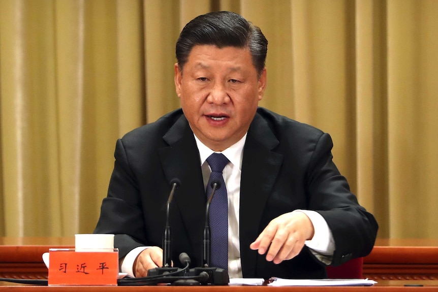 Chinese President Xi Jinping sits behind a gold-coloured curtain at a press conference