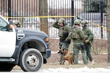 Police standing outside the Molson Coors Company with guns and an attack dog.