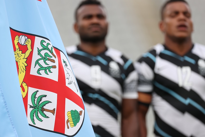 The Fiji flag in front of the Fiji 7s team