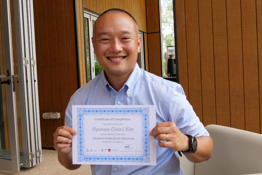 man holds certificate smiling at camera