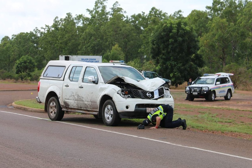 Extensive damage to the bonnet of a four wheel drive is inspected by a police officer.