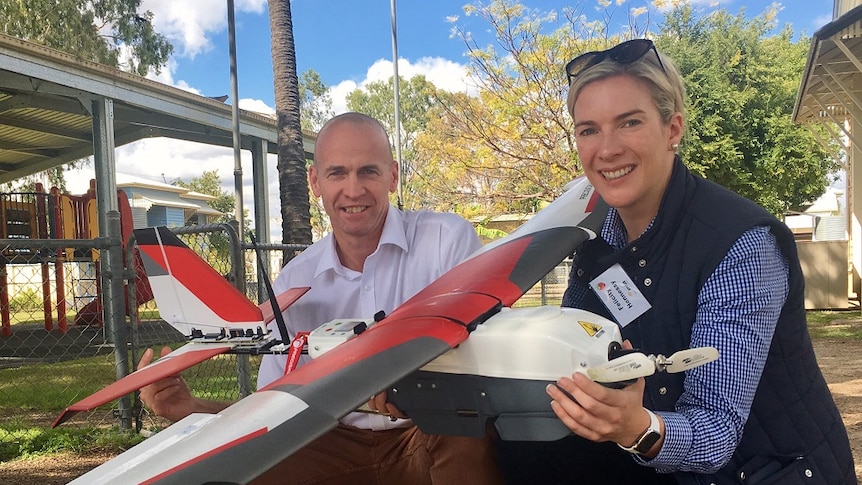 A close up of Sean Starley and Felicity Hennessey and a large white, red and black drone.