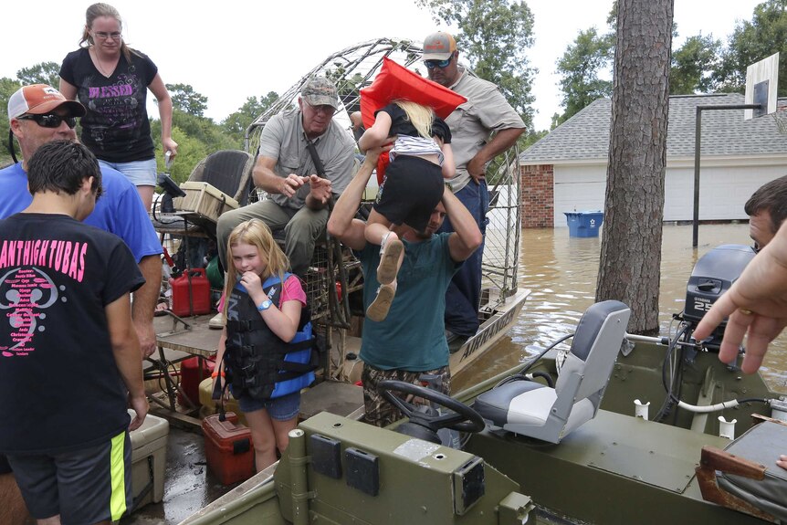 Children are passed into a boat sitting in the flooded Louisiana parish of Ascension.