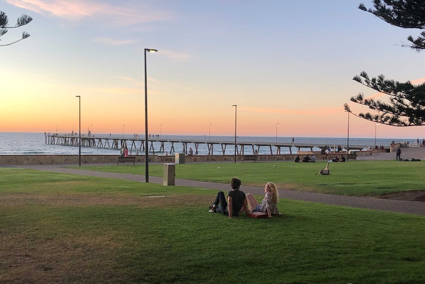 A jetty and park at sunset with two people looking at it