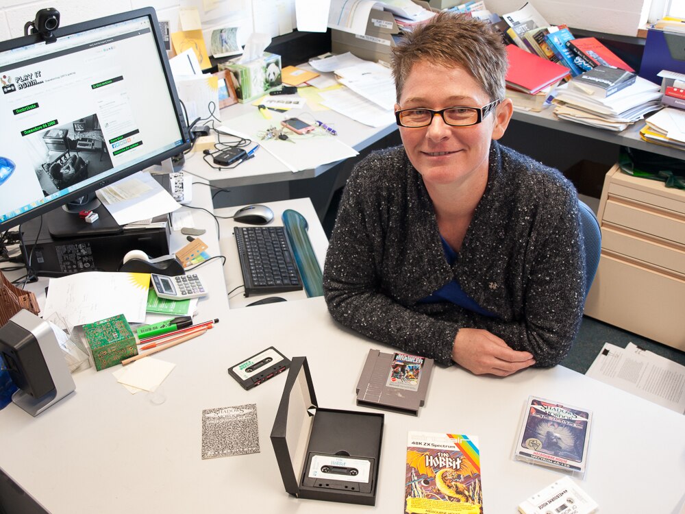 Associate Professor Melanie Swalwell with a small collection of 80s micro-computer games made by Australian programmers.