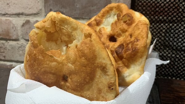 Fried flatbreads wrapped in paper napkin seved in bowl.