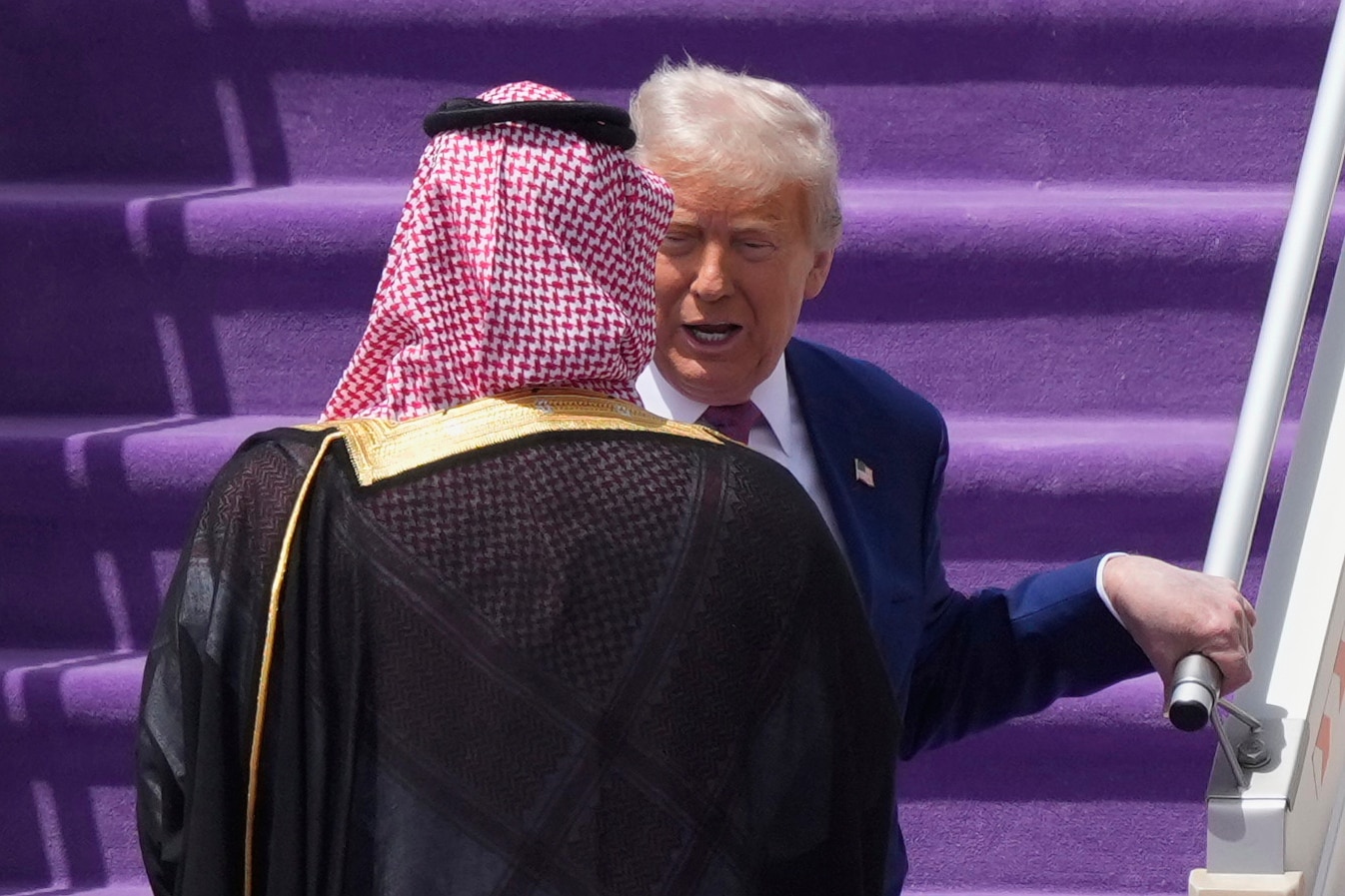 Trump walking down some plane stairs to meet the Saudi Crown Prince.