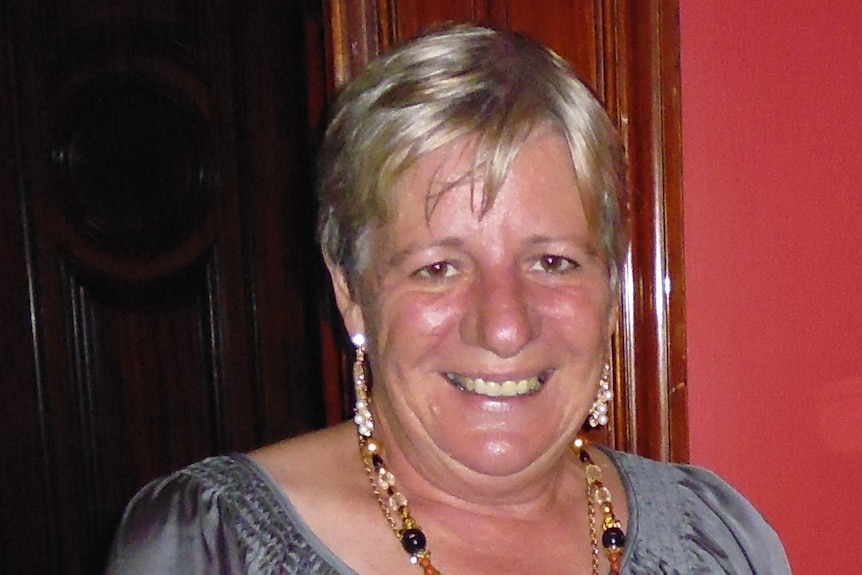 A middle aged woman with short blonde hair smiles. 