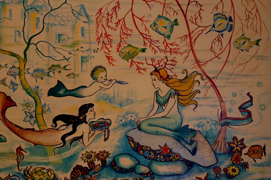A colourful painting, depicting an undersea scene, including mermaids, fish and corals.