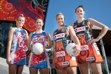 Four players, two from the Swifts, two from the Giants, pose in front of Indigenous artwork on the outside of an area.