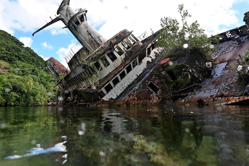 the wreck of MS World Discoverer sitting on its side in shallow water in Roderick Bay in the Solomon Islands.