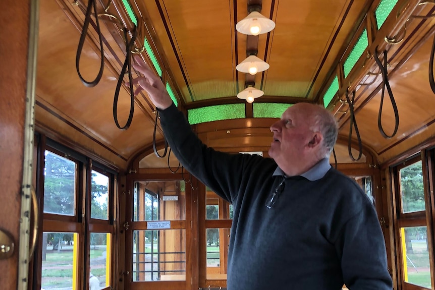 An elderly man points at details inside a tram carriage