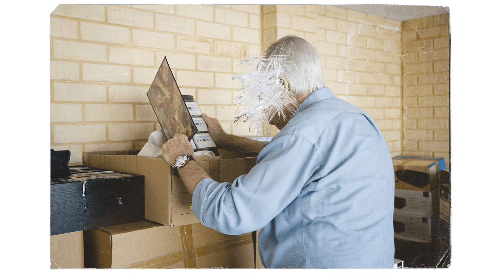 Dan looks at a folder of cassettes on top of a stack of cardboard boxes