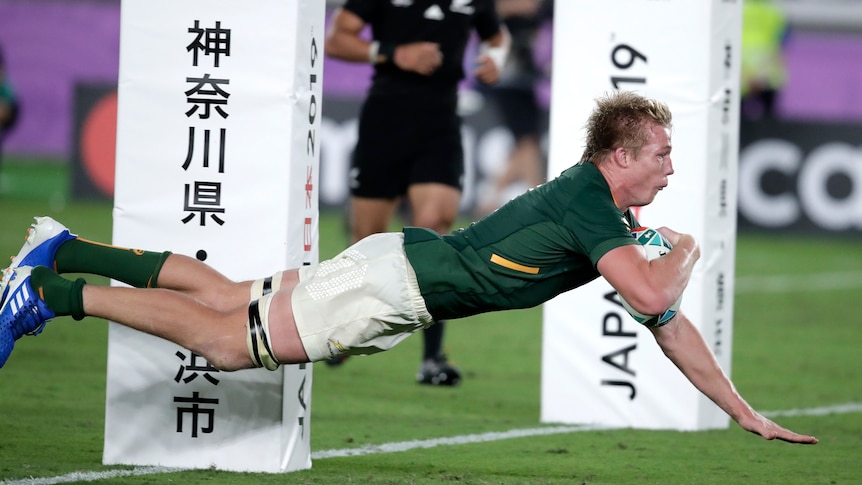 Pieter-Steph du Toit dives over the line next to the padded posts with the ball under his left arm and right arm outstretched