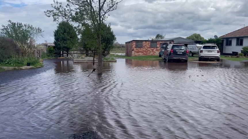 Water covering ground near rural houses and two cars