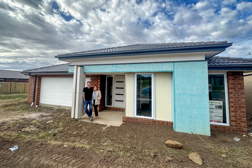 Travis and Noeleen stand outside their nearly finished home