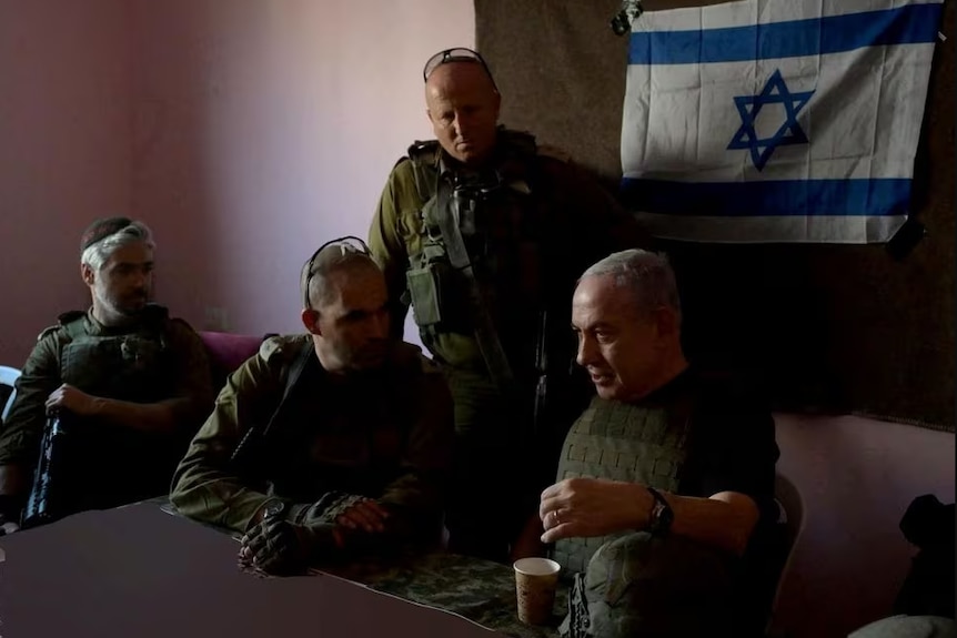 Four men dressed in army clothing sit at a table