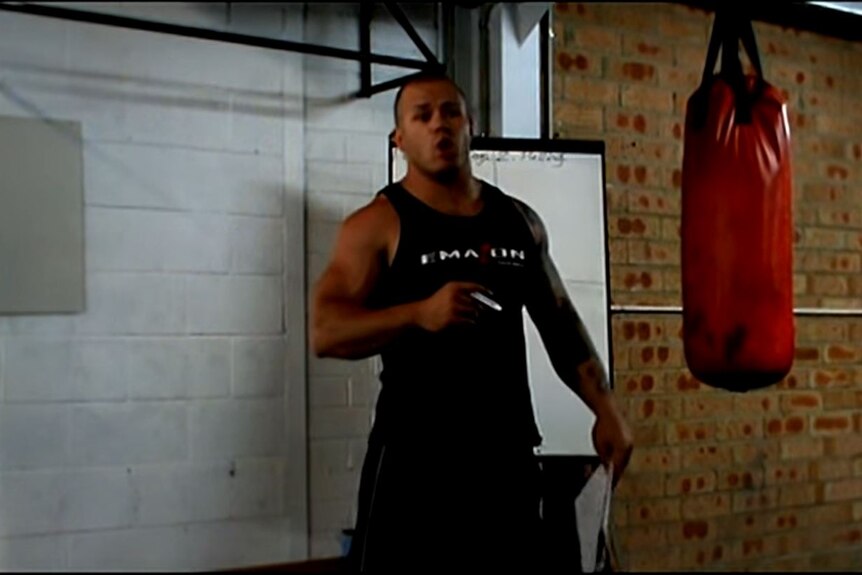 A man in a singlet in a boxing gym.