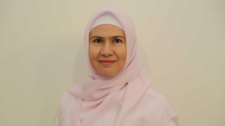 A woman wearing a headcover standing in front of a wall.