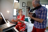 A woman sits at a piano and a man plays guitar for story on share housing when retired.