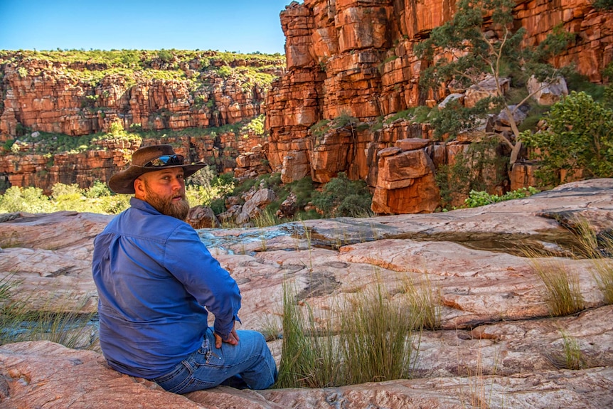 Helicopter pilot Dan Elliot sitting on the side of a gorge.