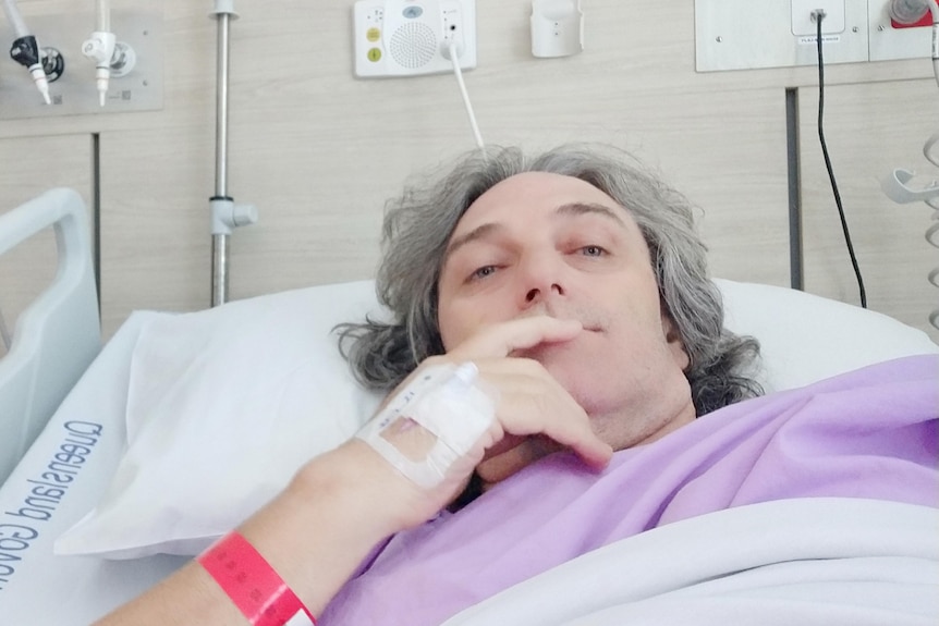 a man with grey haior lying back in a hospital bed