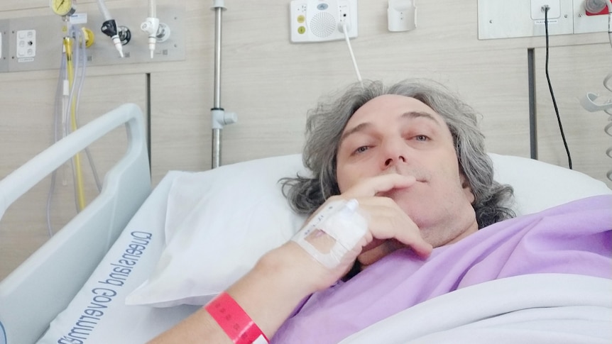 a man with grey haior lying back in a hospital bed