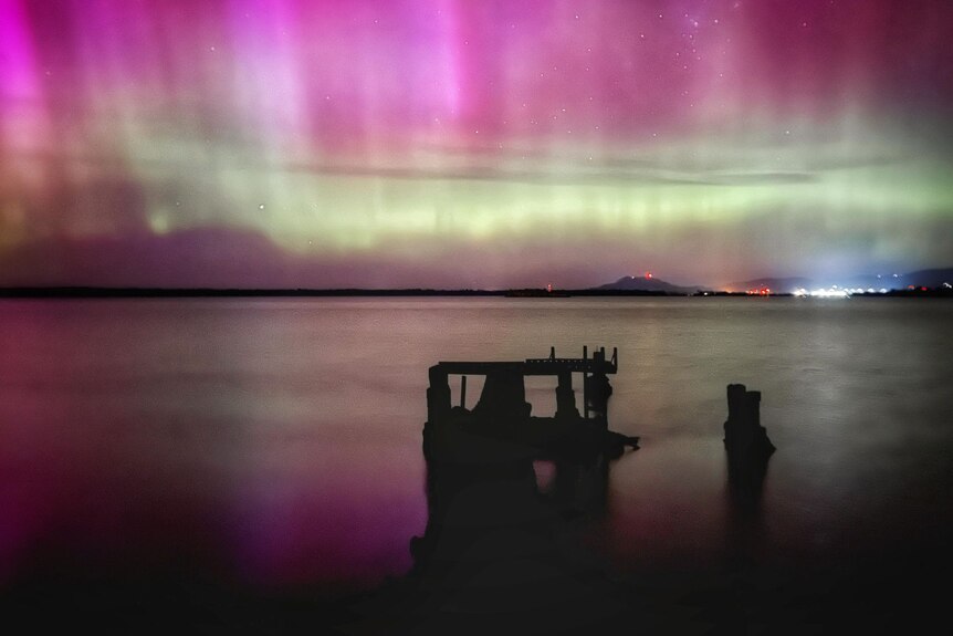 Purple lights in the sky over water.