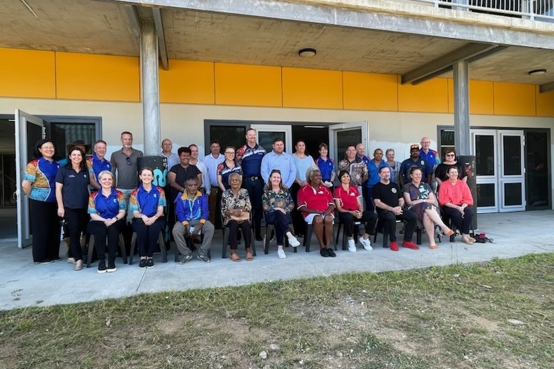 Dozens of people sit outside building on Palm Island.