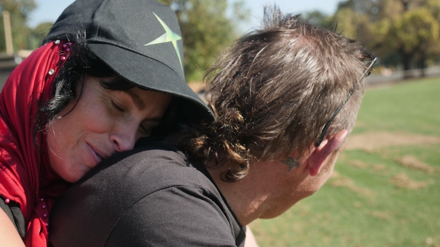 A woman hugs a man from behind. 