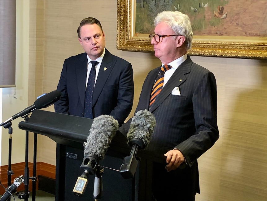 Two men stand behind a lectern. 