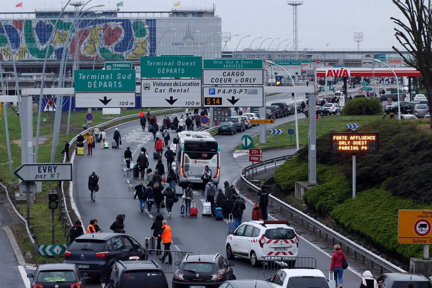 Travellers walk on the highway to the Orly Airport as passengers were evacuated.