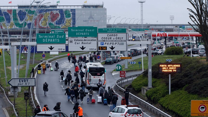 Travellers walk on the highway to the Orly Airport as passengers were evacuated.