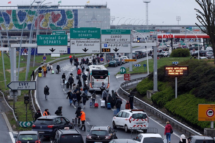 Travellers walk on the highway to the Orly Airport as passengers were evacuated.