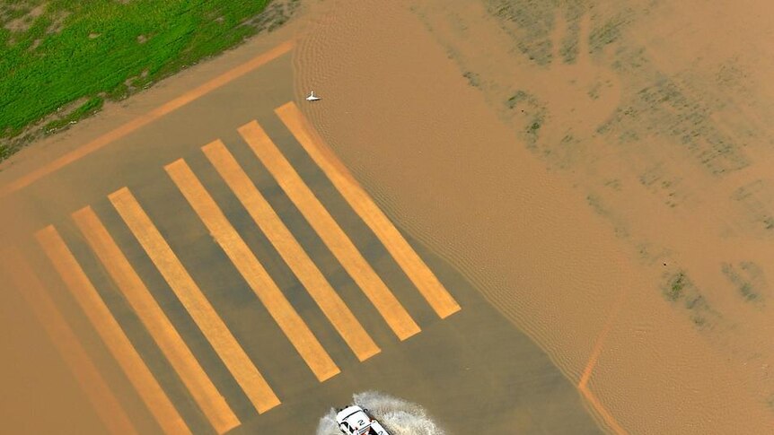 A vehicle drives down the flooded runway at Rockhampton Airport
