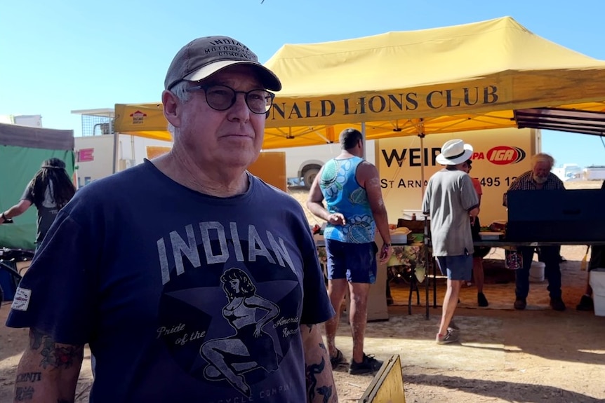 a man stands in front of a "Donald Lions Club" tent.