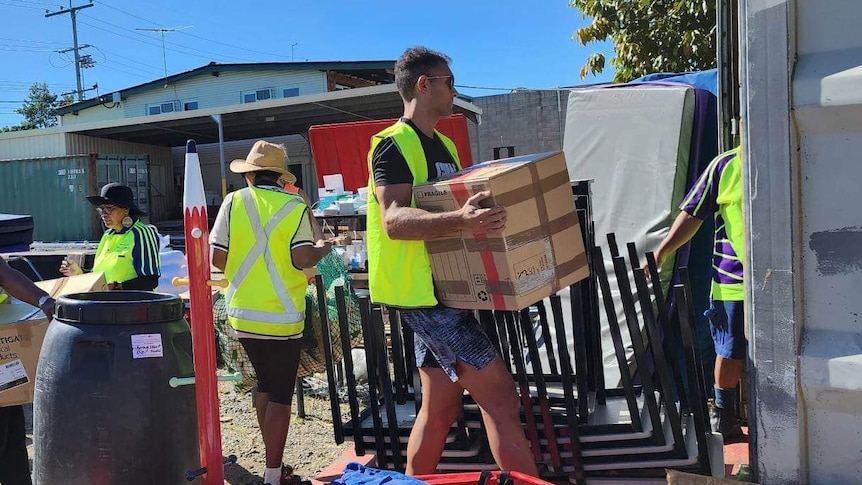 Group of people in high vis pack a shipping container