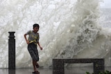 A boy plays in front of waves triggered by tropical storm Goni.