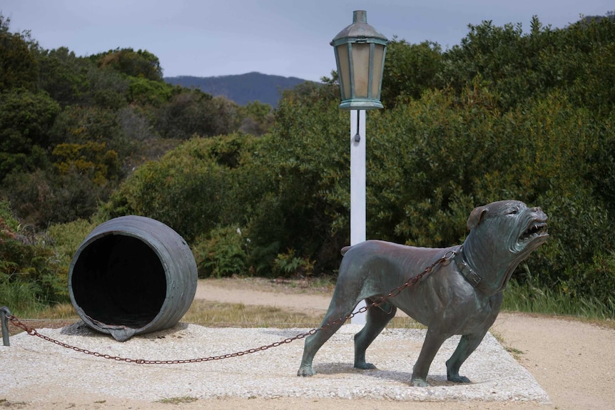 Picture of a statue of a vicious dog, with a lamp pose and barrel